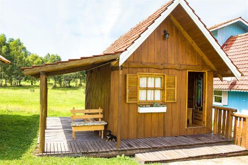 a small wooden cabin with a bench on a deck at Pousada Rural Pavão in Urubici