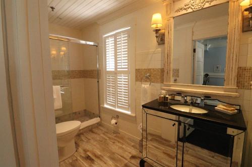 a bathroom with a sink and a toilet and a mirror at The Riverview Hotel - New Smyrna Beach in New Smyrna Beach