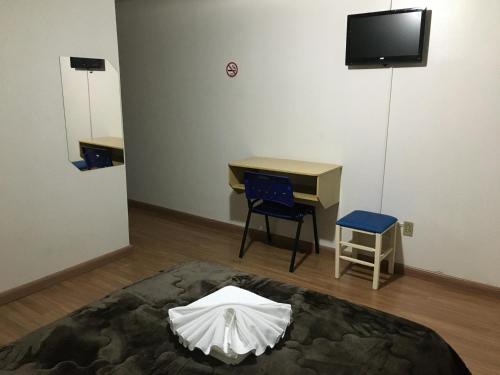 a room with a bed and a desk and a tv at Hotel Fontana in Tapejara