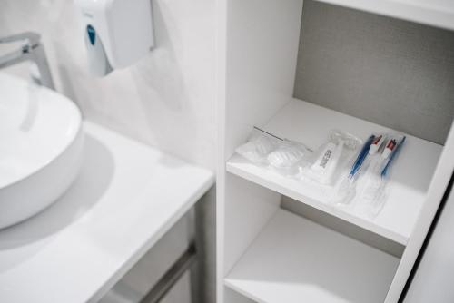 a white bathroom with a sink and toothbrushes at Чевермето-Ірен in Luts'k