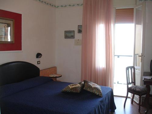a bedroom with a blue bed and a window at Hotel Primavera sul mare in Lido di Savio