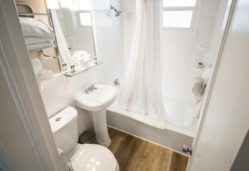 a white bathroom with a toilet and a sink at Ocean Reef Suites in Miami Beach