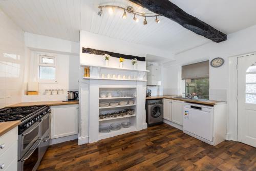 cocina grande con armarios blancos y fogones en Muncaster Cottages en Ravenglass