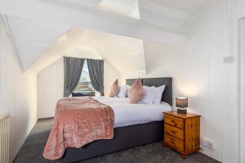 a bedroom with a large bed and a window at Muncaster Cottages in Ravenglass