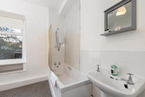 a white bathroom with a sink and a mirror at Muncaster Cottages in Ravenglass