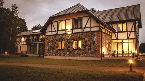 a large house with a stone facade at night at Usmas muiža in Usma