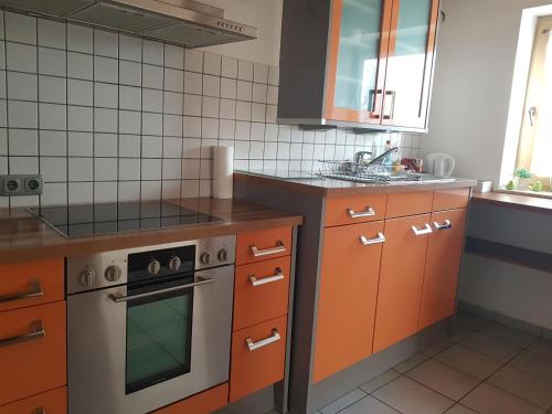 a kitchen with orange cabinets and a stove at Apartment am Riegelberg in Oesdorf