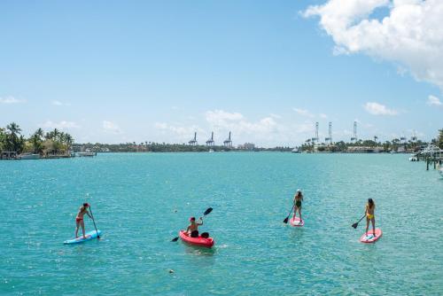 
people on surfboards in the water at Ocean Reef Suites in Miami Beach
