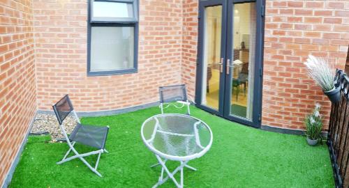 two chairs and a table on the grass next to a brick building at Long Row Apartments in Nottingham City Centre in Nottingham