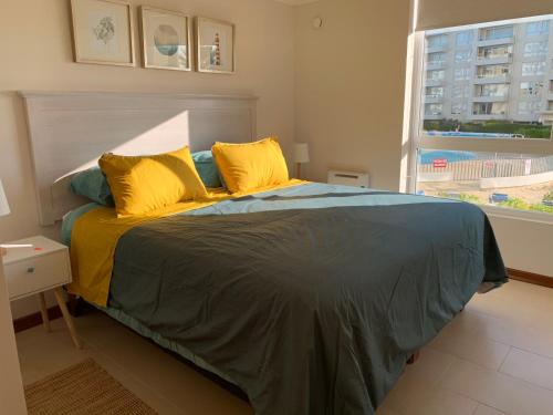 a bedroom with a bed with yellow pillows and a window at Papudo Laguna in Papudo