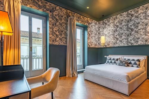 a bedroom with a bed and a desk and windows at Voluta Suites in Milan