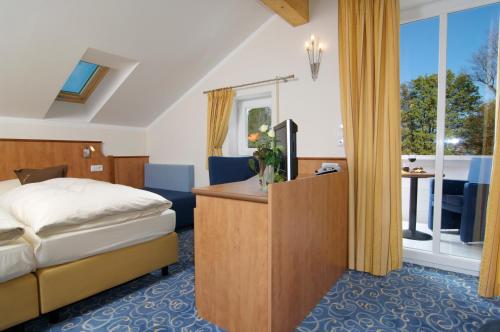 a bedroom with a bed and a desk and a window at Hotel Gasthof Seefelder Hof in Dießen am Ammersee