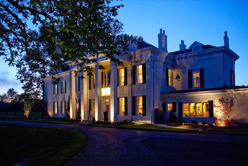 a large white house with its lights on at Riverside Inn Bed and Breakfast in Warsaw