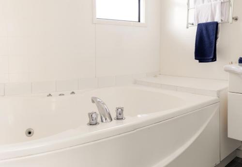een witte badkamer met een bad en een wastafel bij Snells Beach Motel in Snells Beach