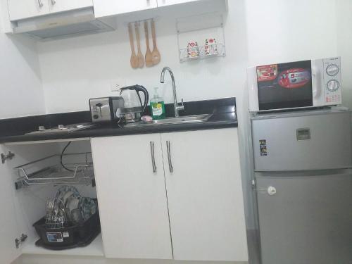 La cuisine est équipée de placards blancs, d'un évier et d'un réfrigérateur. dans l'établissement Jazz Hunter Residence, à Manille