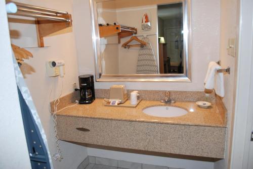 eine Badezimmertheke mit einem Waschbecken und einem Spiegel in der Unterkunft Scottish Inns in DeSoto