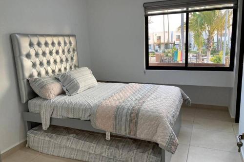 a bed sitting in a room with a window at Preciosa Enjoyable Casa 12 Personas Alberca Playa Coto 24H in Mazatlán