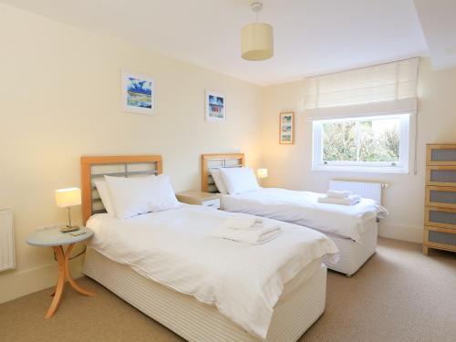 a bedroom with two beds and a window at 14 Combehaven in Salcombe