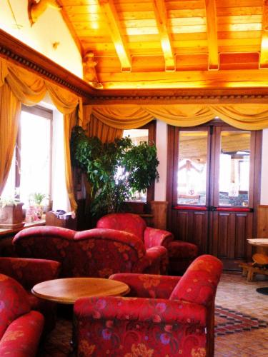 a living room with red chairs and a table at Hotel Beau Sejour in Etroubles