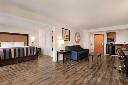 a hotel room with a bed and a living room at Wingate By Wyndham Montgomery in Montgomery