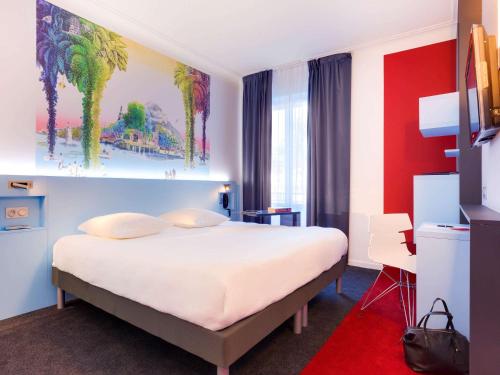 a bedroom with a white bed with a painting on the wall at ibis Styles Nantes Centre Gare in Nantes