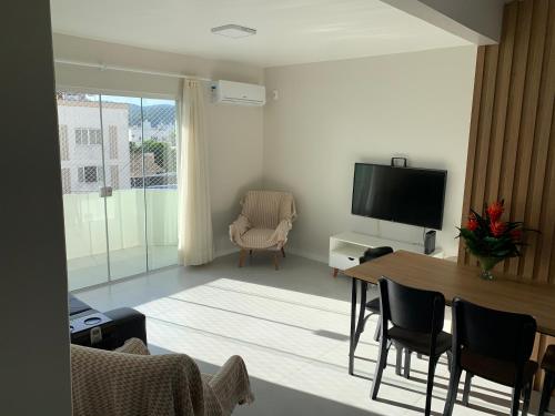 ein Wohnzimmer mit einem Tisch und einem TV in der Unterkunft Apartamento 3100 in Balneário Camboriú