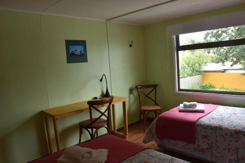a bedroom with a bed and a desk and a window at Asói Hostal in Puerto Natales
