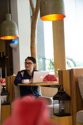 a man sitting at a table with a laptop computer at PrimeBiz Cikarang in Cikarang