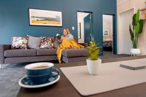 a woman sitting on a couch in a living room at Hanmer Springs TOP 10 Holiday Park in Hanmer Springs