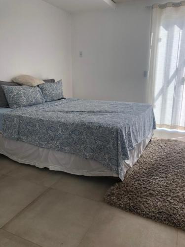 1 dormitorio con 1 cama con manta azul y alfombra en Casa espaçosa cpm linda vista pro verde, en Búzios