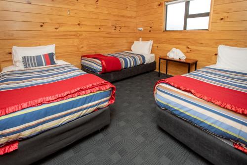 two beds in a room with wooden walls at Hanmer Springs TOP 10 Holiday Park in Hanmer Springs