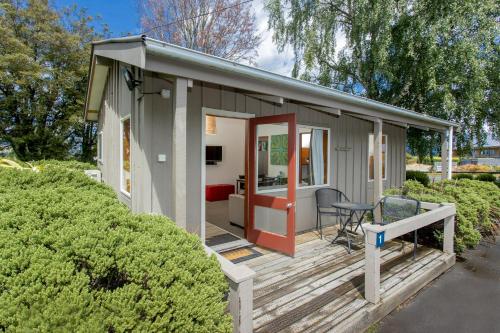 a tiny house with a red door on a deck at Hanmer Springs TOP 10 Holiday Park in Hanmer Springs