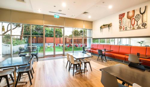 a restaurant with tables and chairs and windows at ibis Melbourne - Glen Waverley in Glen Waverley