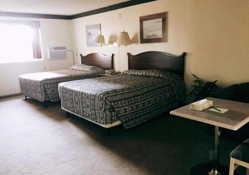 a hotel room with two beds and a table at Hi Valley Motor Inn in Valleyview