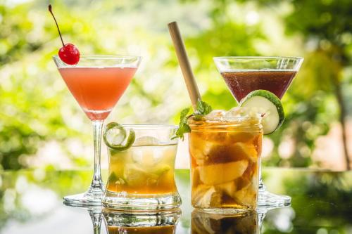 a group of three cocktails sitting on a table at Ock Pop Tok Mekong Villa in Luang Prabang
