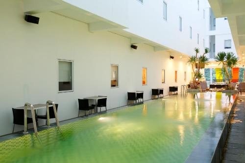 a swimming pool in a building with chairs and tables at Amaris Hotel Sunset Road - Bali in Kuta