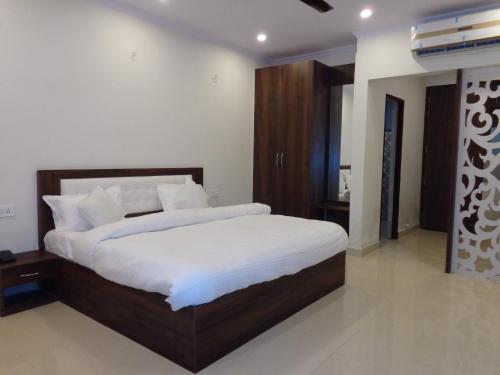 a bedroom with a large bed with white sheets at Rukmani Inn in Vrindāvan