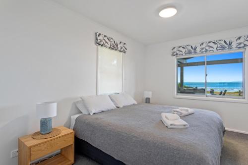 a bedroom with a bed and a window with the ocean at Kohi Point - Ohope Beachfront Holiday Home in Ohope Beach