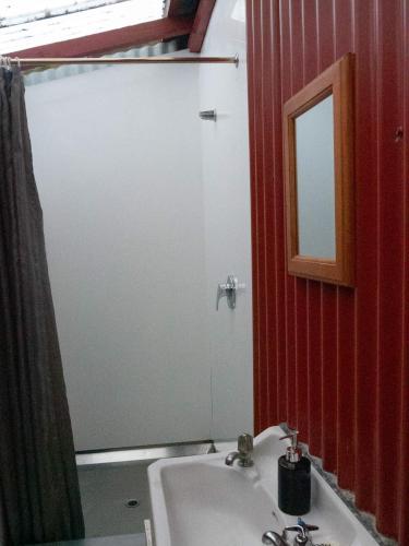 a bathroom with a sink and a shower with a mirror at Te Nikau Retreat in Punakaiki