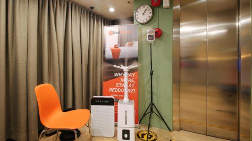 an orange chair and a clock in a room at RedDoorz at Hotel Rosemarie in Manila