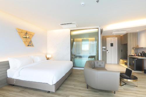 a bedroom with a bed and a couch and a chair at The Signature Hotel Airport in Hat Yai