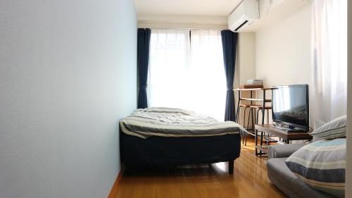 a room with a bed and a couch and a tv at Victoire Kagurazaka301 in Tokyo