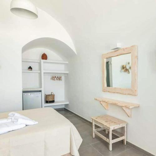 a white room with a bed and a mirror at Villa Thiranthemis in Fira