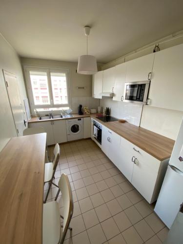 une cuisine avec des armoires blanches et une table et des chaises dans l'établissement Chambre calme (Venus) - Proche Gare & Hyper centre, au Mans