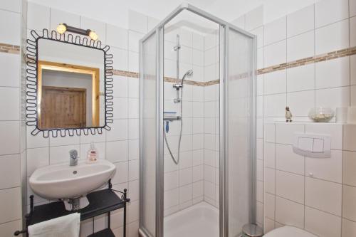 ein weißes Badezimmer mit Waschbecken und Dusche in der Unterkunft Ostseehaus Lea Doppelhaushälfte in Wiek auf Rügen 