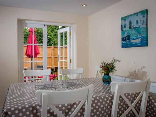 een eettafel met witte stoelen en een roze parasol bij Vicarage Cottage in Kenton