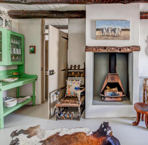 a living room with a fireplace and a chair at De Kale Kat in Greyton