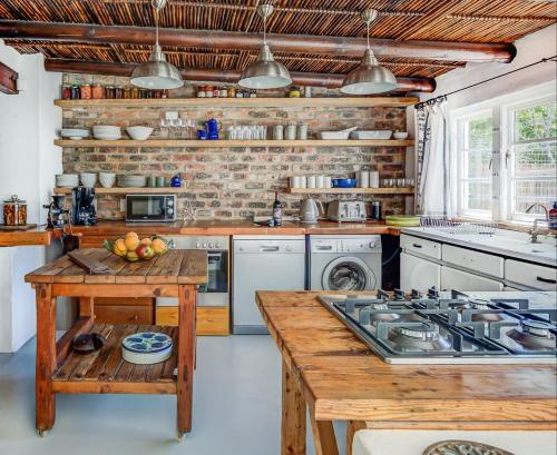 a kitchen with white appliances and a wooden table at De Kale Kat in Greyton