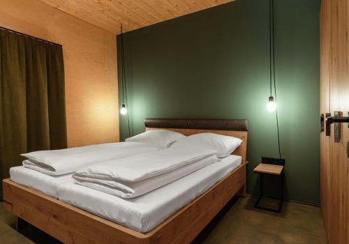 uma cama com almofadas brancas e uma parede verde em Apartment Hoamelig em Wald am Arlberg