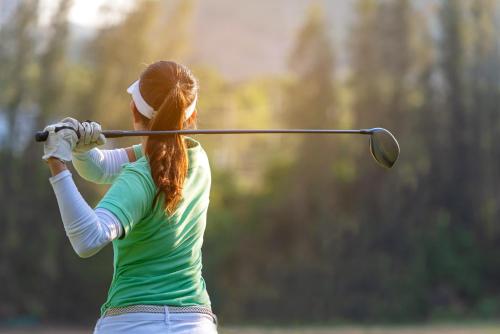 a woman hitting a golf ball with a club at Naturhotel Edelweiss Wagrain in Wagrain
